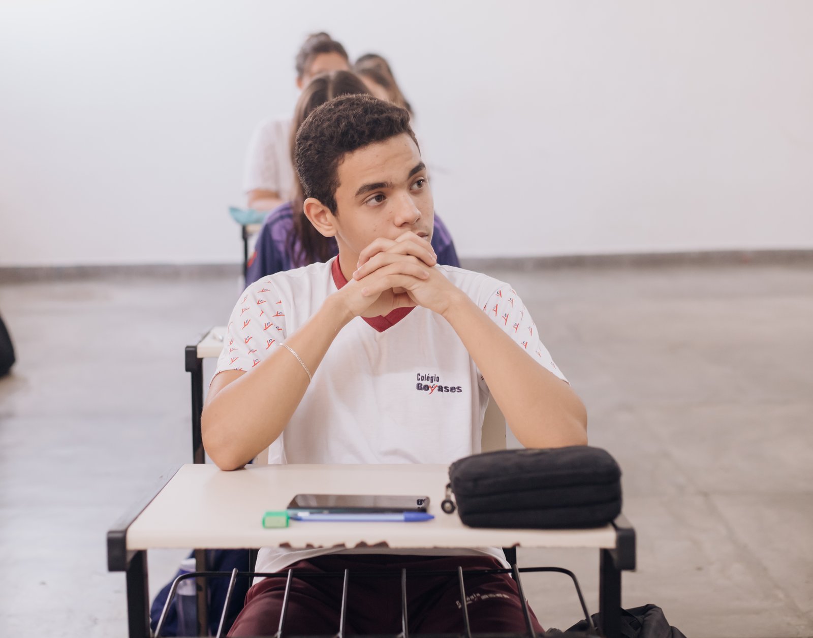 Aluno do Anos Finais atento em sala de aula, com colegas ao fundo