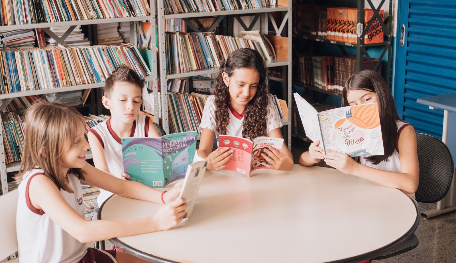 Alunas dos Anos Iniciais lendo em mesa redonda na biblioteca